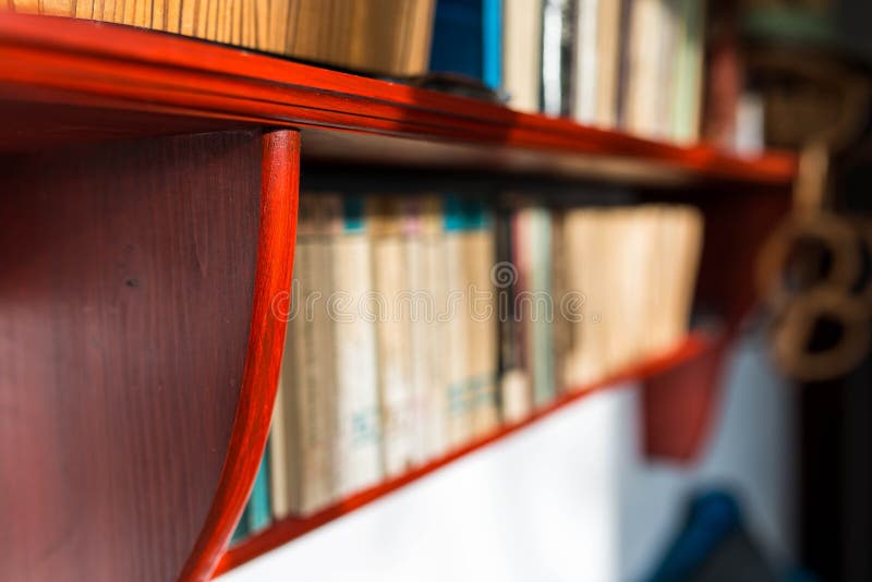 Pine wood book shelf close up shot, books in row on the blurred background.