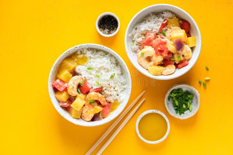 Pineapple and shrimp curry with white rice in bowl on yellow background. Table top view. Asian cuisine food