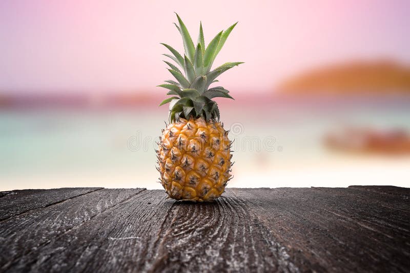 Pineapple on wooden desk and beach side background with clipping path
