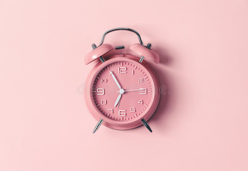Classic Pink Alarm Clock Ringing at Seven O`clock Against Pastel Pink