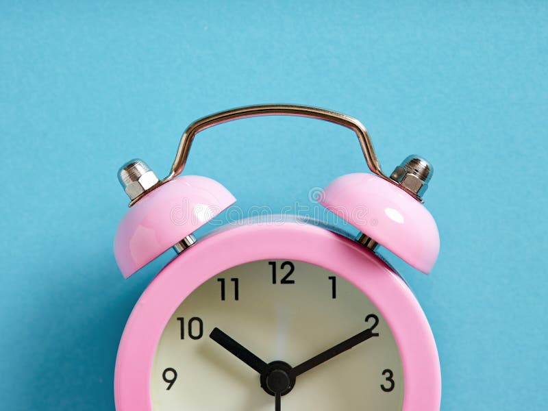 Pink Alarm Clock on Blue Background. Close Up Macro View Stock Photo