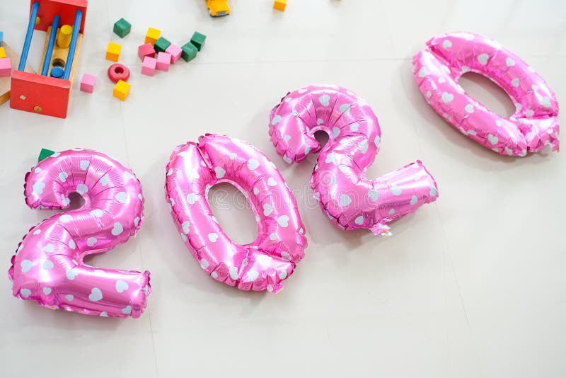 Pink balloons put on the floor together near various type of toys with the text mean to year 2020 or two thousand and twenty royalty free stock photography Pink balloons put on the floor together near various type of toys with the text mean to year 2020 or two thousand and twenty royalty free stock photography