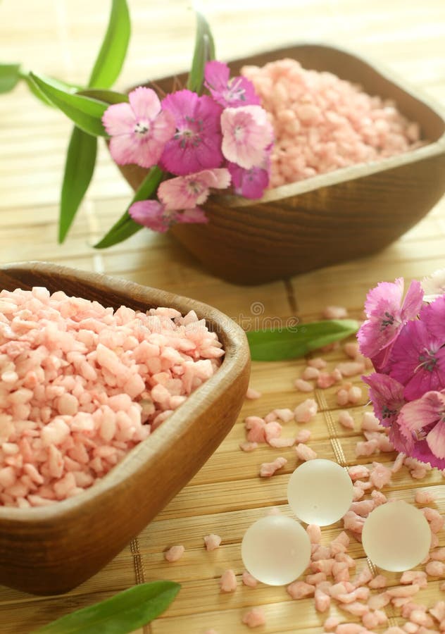 Pink bath salts in wooden bowls and flowers.