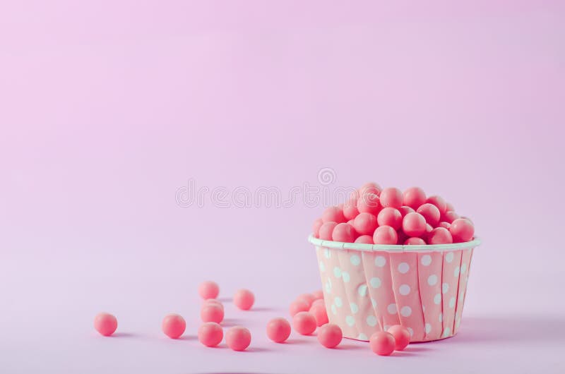 Pink candies in pink paper cup with white polka dot pattern on p