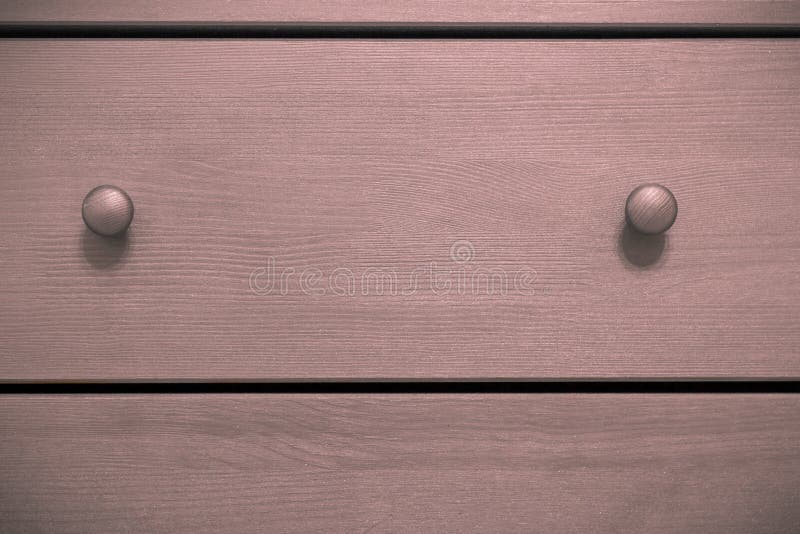 Pink chest of drawers with handles, wooden background