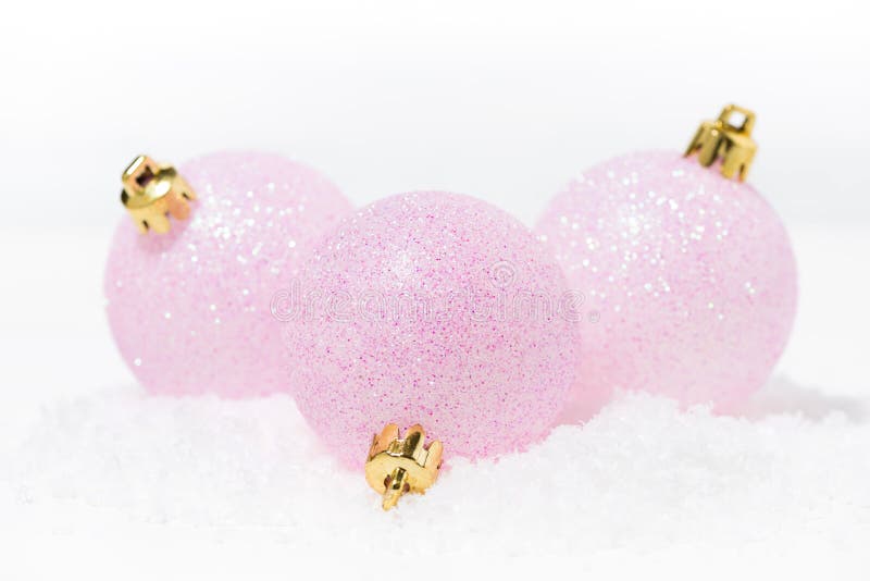 pink christmas balls in the snow on a white background