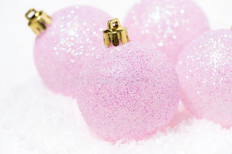 pink christmas balls in the snow on a white background, closeup