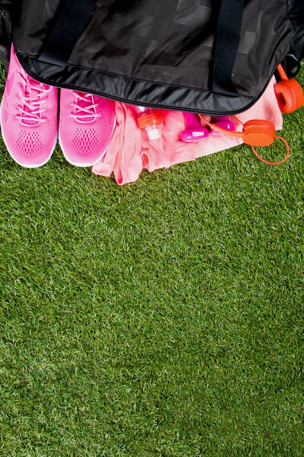 Pink clothes and accessories for fitness, a bottle of water, in a black sports bag, on the background of grass stock photo Pink clothes and accessories for fitness, a bottle of water, in a black sports bag, on the background of grass stock photo