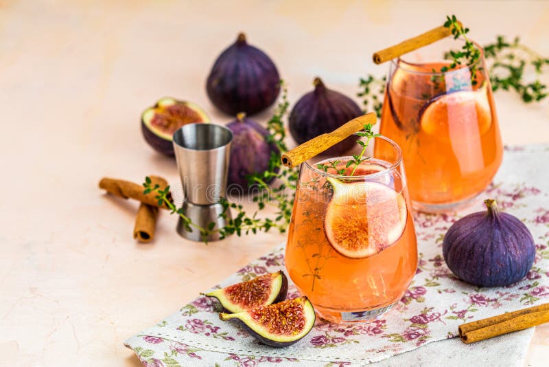 Pink cocktail with fig, thyme and ice in glass on pink concrete background, close up