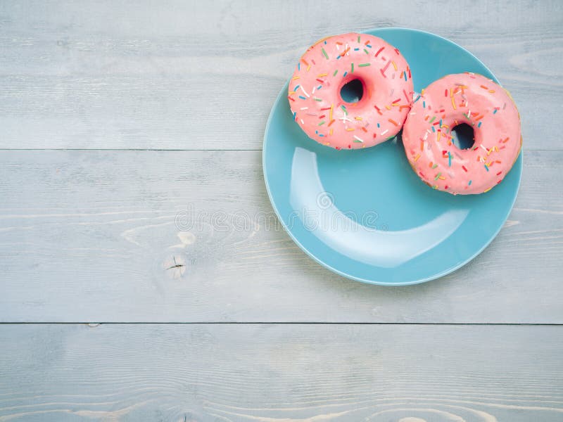 Pink donuts on gray wooden background, copy space, top view