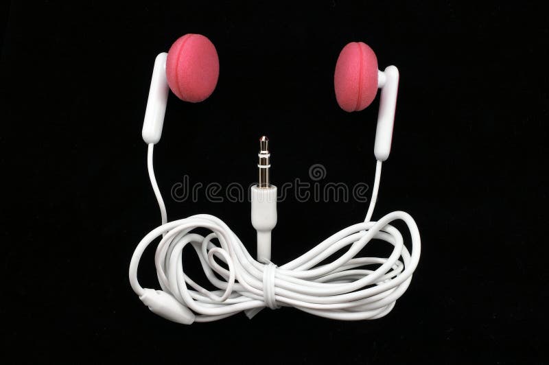 Pink Earbuds Closeup, macro, on white, with wire and plug arranged as a smiling face on black background. Pink Earbuds Closeup, macro, on white, with wire and plug arranged as a smiling face on black background