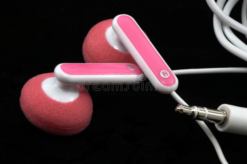 Pink Earbuds Closeup, macro, on white with wires and stereo plug, on black background. Pink Earbuds Closeup, macro, on white with wires and stereo plug, on black background