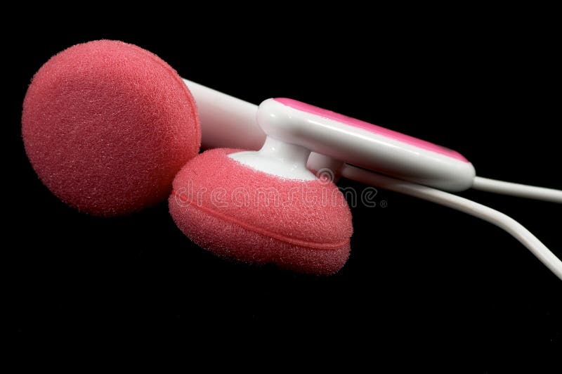 Pink Earbuds Closeup, macro, on white with wires and stereo plug, on black background. Pink Earbuds Closeup, macro, on white with wires and stereo plug, on black background