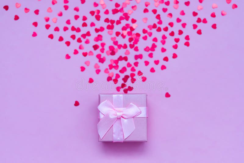 Pink gift box with holographic red hearts on pastel background. Festive backdrop. Top view royalty free stock images Pink gift box with holographic red hearts on pastel background. Festive backdrop. Top view royalty free stock images