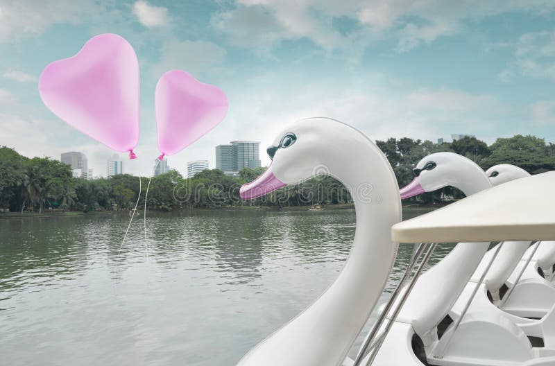 Pink heart love balloon float on air with swan pedal boat at public park, vintage style