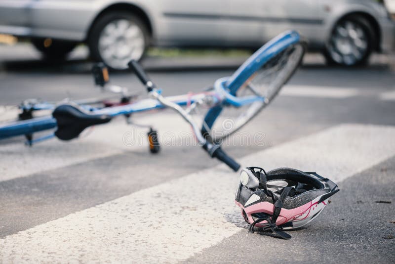 Pink helmet and blue kid`s bike on pedestrian crossing after inc. Ident with a car stock image