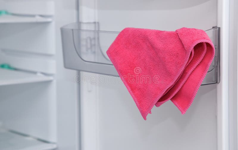 A pink new microfiber rag, towel, weighs on a clean shelf in a white refrigerator. royalty free stock image