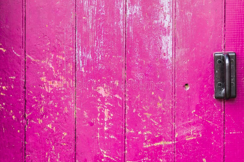 Pink old wooden door scarred with black handle