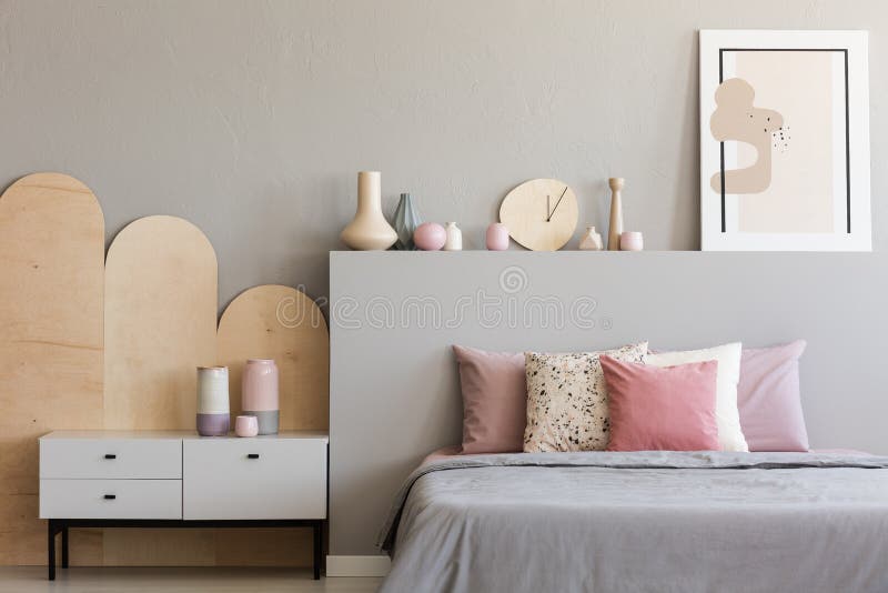 Pink pillows on grey bed in modern bedroom interior with poster