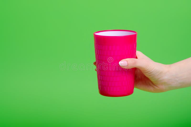 Pink plastic cup in hand stock image. Image of pink