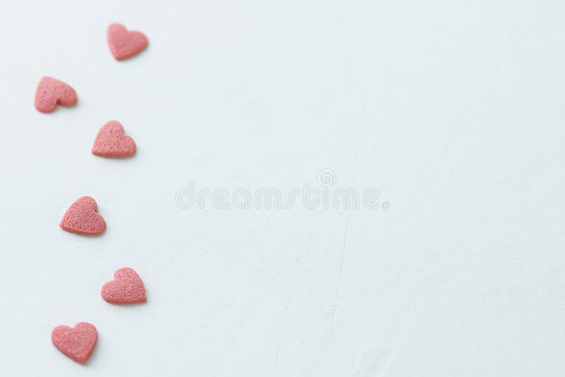 Pink Red Sugar Sprinkles Candies in Heart Shape Scattered on White Background Border Frame. Valentine Romance Birthday Charity Sym