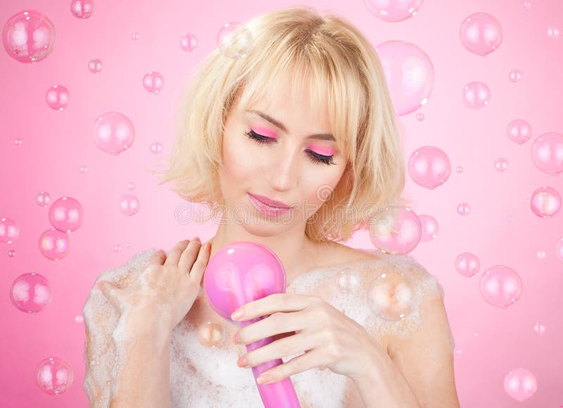 Beautiful happy young girl having a bath with pink shower