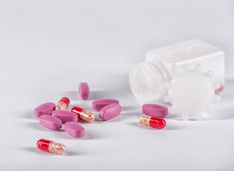 Pink Tablets and Red Pills Near the Lying Plastic Bottle Stock Photo