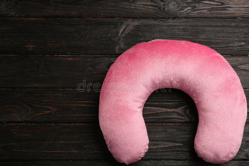 Pink travel pillow on wooden background. Space for text royalty free stock images