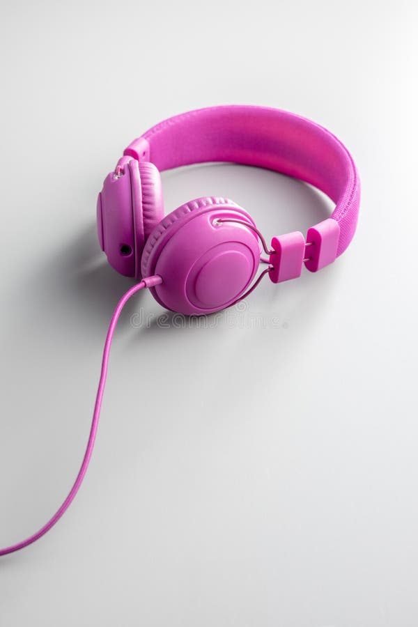 Pink wired stereo headphones on gray background. Pink wired stereo headphones on a gray background