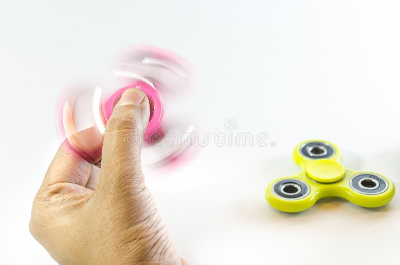 Two fidget spinner one moving one is not moving. Pink and yellow colour fidget spinner moving in a motion holding by a hand and still condition in white background