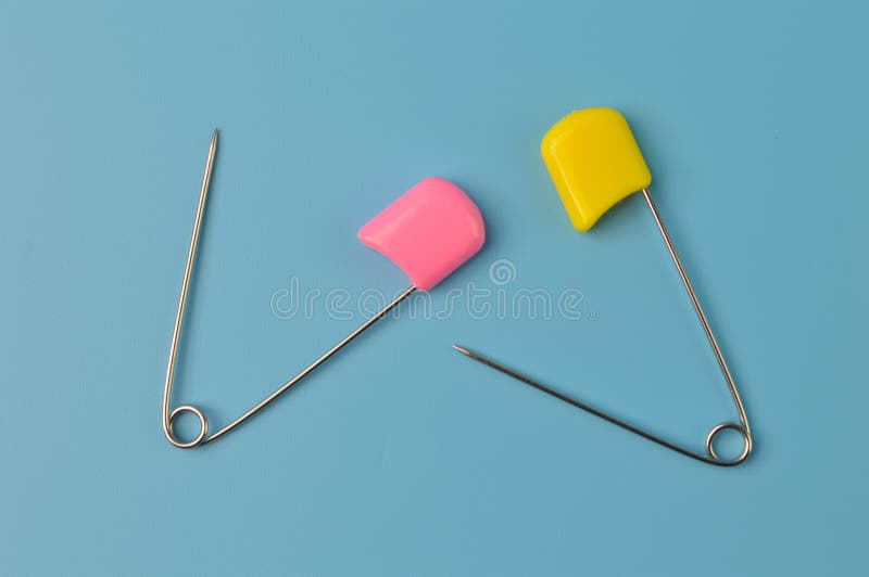 Pink and Yellow Safety Pins Isolated on a Blue Background Stock Image