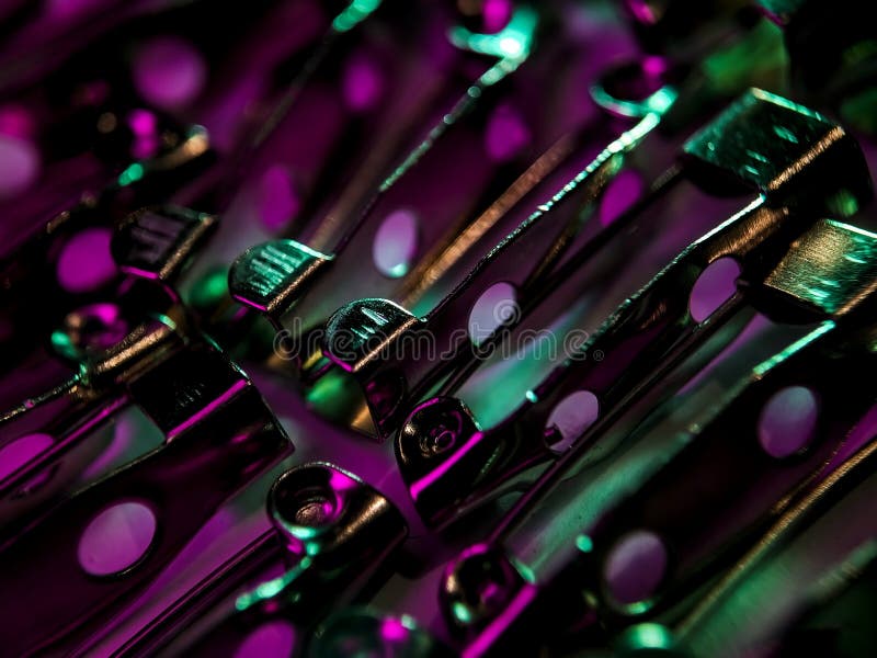 The pins are metallic, reflecting the light, which highlights their contours and openings. The shadows enhance the overlapping structure, giving a textured and layered appearance. The focus is sharp on the pins, emphasizing their simple mechanism and functionality. Disco violet light stock images, royalty-free photos and pictures