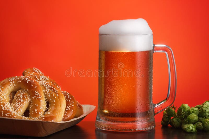 Pint van bier met ingrediënten voor eigengemaakt bier op rood met pretzel stock afbeelding Pint van bier met ingrediënten voor eigengemaakt bier op rood met pretzel stock afbeelding