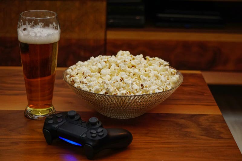 Pinta della ciotola della birra di popcorn e di gamepad su home entertainment di legno del fondo fotografie stock libere da diritti
