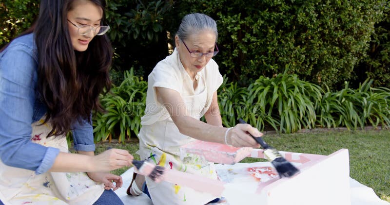 Pintando juntos al aire libre mujeres mayores y mujeres jóvenes disfrutando de la actividad creativa metrajes