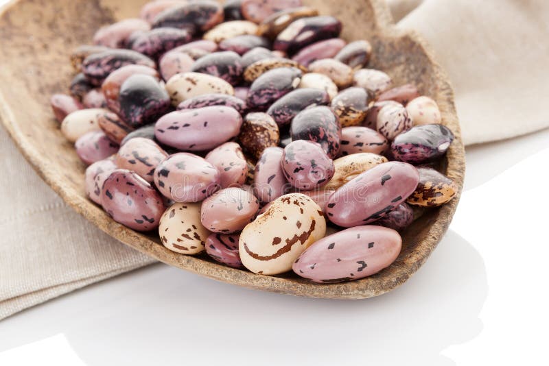 Pinto beans on wooden scoop on beige table cloth. Healthy eating, agriculture background. Pinto beans on wooden scoop on beige table cloth. Healthy eating, agriculture background.