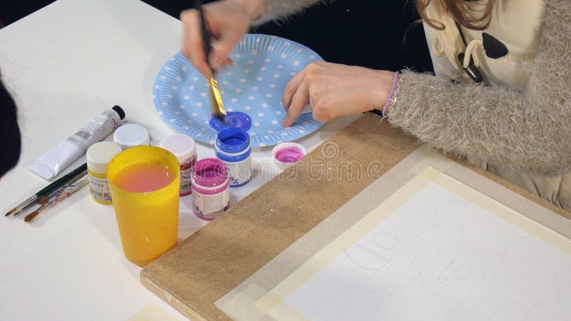 Pintura de las mujeres adultas con las pinturas acrílicas coloreadas en un cierre de la escuela de arte para arriba