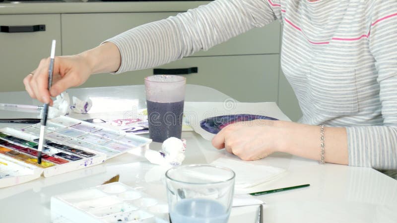 Pintura de las mujeres adultas con las pinturas coloreadas de la acuarela en un estudio casero