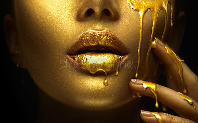 A pintura dourada borra gotejamentos dos bordos da cara e da mão, gotas líquidas douradas na boca da menina bonita do modelo, com imagem de stock royalty free A pintura dourada borra gotejamentos dos bordos da cara e da mão, gotas líquidas douradas na boca da menina bonita do modelo, com imagem de stock royalty free