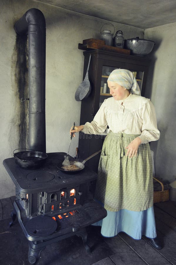 A pioneer woman cooking bratwurst on an old fashioned cast iron stove at Old World, Wisconsin in Eagle, WI. A pioneer woman cooking bratwurst on an old fashioned cast iron stove at Old World, Wisconsin in Eagle, WI.