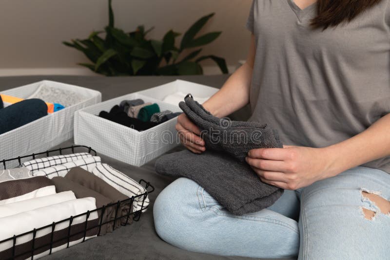 Vertical storage of clothing.Women organize clothes in a modern bedroom. Women sorting clothes in baskets room cleaning concept in a natural light. Vertical storage of clothing.Women organize clothes in a modern bedroom. Women sorting clothes in baskets room cleaning concept in a natural light