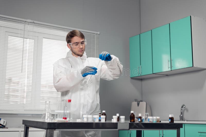 Pipette in hand. Technician in blue gloves pouring something into the test tube and looking busy royalty free stock photo