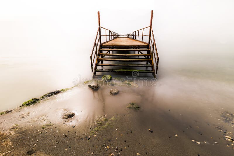 Pir i ljuset Lyftt plattform som byggs från kusten ut över havet, vatten, sjö Du kan fiske eller simning härifrån royaltyfri bild Pir i ljuset Lyftt plattform som byggs från kusten ut över havet, vatten, sjö Du kan fiske eller simning härifrån royaltyfri bild