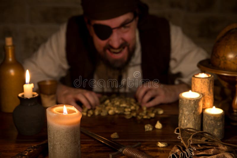 Piraat met een schat van goud achter heel wat kaarsen stock foto's Piraat met een schat van goud achter heel wat kaarsen stock foto's