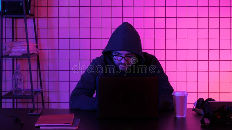 Pirata informático financiero de sexo masculino joven en el trabajo que se sienta de la oficina en el ordenador portátil foto de archivo libre de regalías Pirata informático financiero de sexo masculino joven en el trabajo que se sienta de la oficina en el ordenador portátil foto de archivo libre de regalías