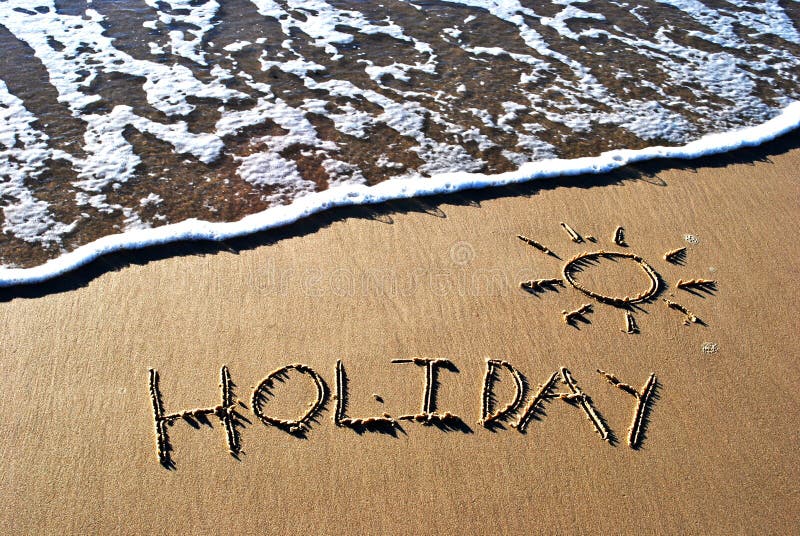 The word holiday written in sand with a wave washing in. The word holiday written in sand with a wave washing in