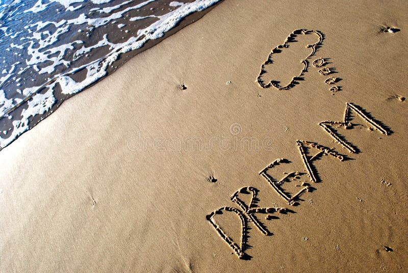 The word dream written on the sand with a wave washing in. The word dream written on the sand with a wave washing in