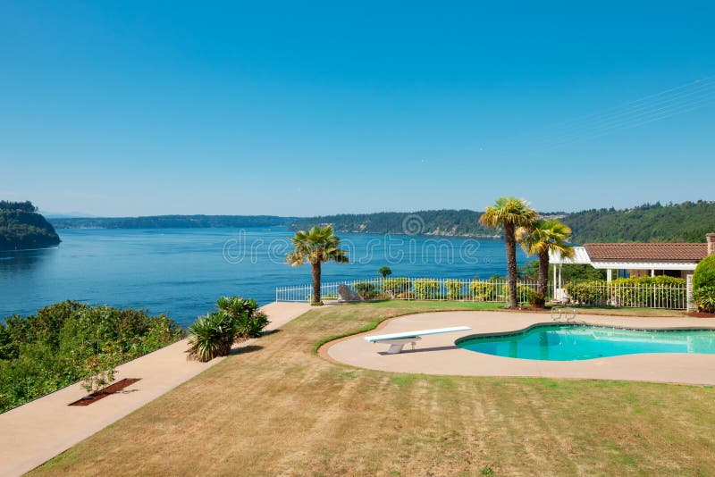 Piscina a la casa de lujo de la costa con el área y la visión grandes o de la hierba imagen de archivo Piscina a la casa de lujo de la costa con el área y la visión grandes o de la hierba imagen de archivo