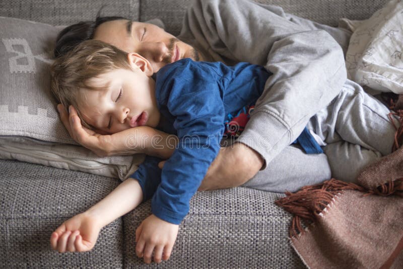 Pisolino del figlio e del padre sullo strato immagine stock Pisolino del figlio e del padre sullo strato immagine stock