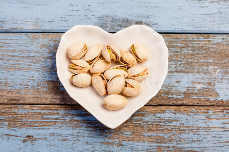 Pistacchi in un a forma di scodella come cuore immagine stock libera da diritti Pistacchi in un a forma di scodella come cuore immagine stock libera da diritti